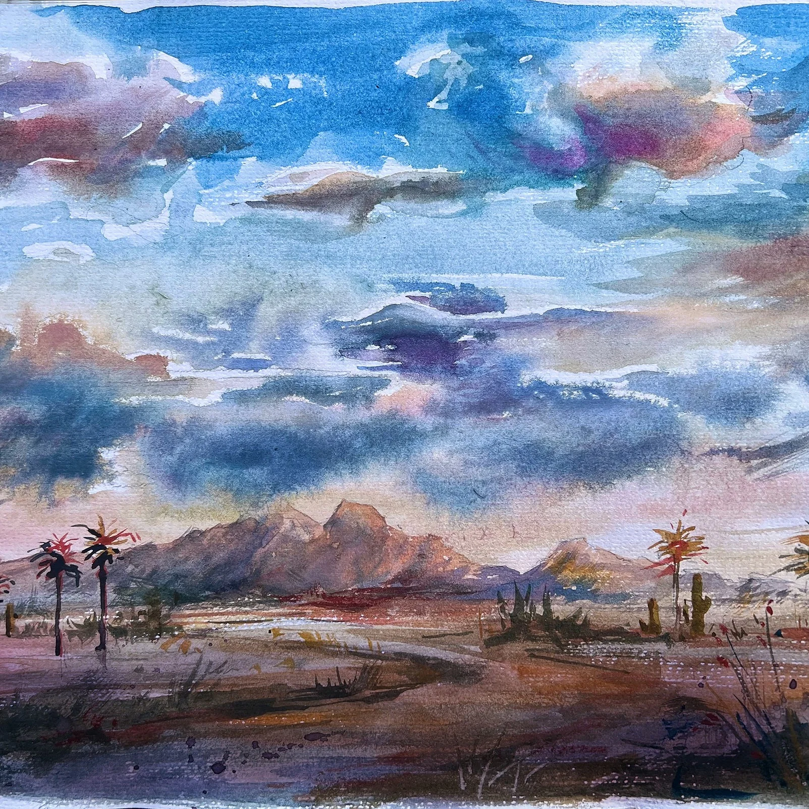 Blue and violet clouds over desert mountains in watercolor